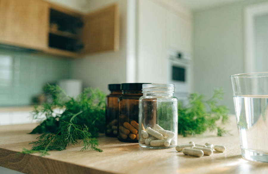 Ongelabelde supplementenpotjes met verse kruiden en een glas water